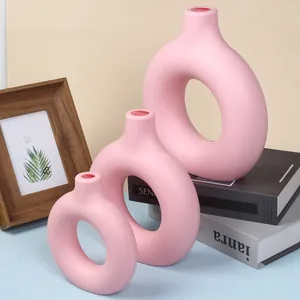 Close-up detail of three pink donut-shaped decorative plastic vases arranged on books