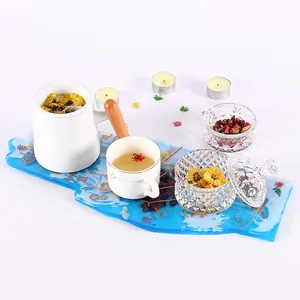Dettaglio di vassoio decorativo in resina blu con set da tè e fiori secchi su bianco