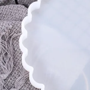 Close-up of the scalloped edge detail on a translucent white silicone mold for DIY crafts