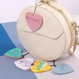 Primo piano di ciondoli a cuore colorati con frasi romantiche su borsa bianca