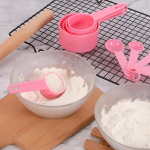 Pink plastic measuring cups and spoons set shown with flour in a lifestyle baking scene