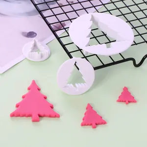 Detailweergave van drie witte kerstboom koekjesvormpjes met roze fondant vormen erop