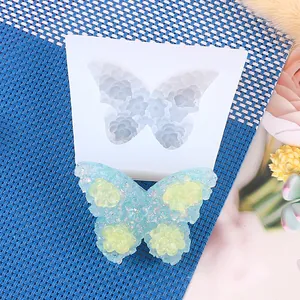 Detailed butterfly silicone mold showing finished glitter resin craft on blue woven mat