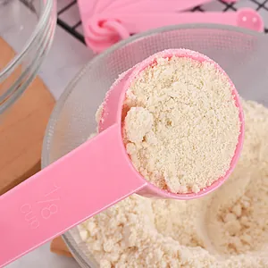 Close-up of a pink 1/8 cup measuring spoon filled with fine white powder for baking