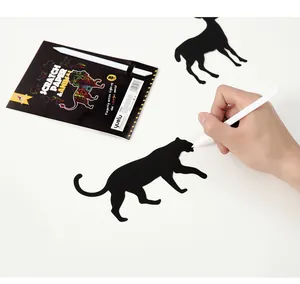 Close-up detailed view of a hand scratching black animal-shaped DIY scratch art paper