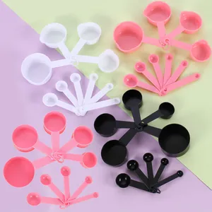Set of 10 plastic measuring spoons and cups in pink, white, and black with embossed scales