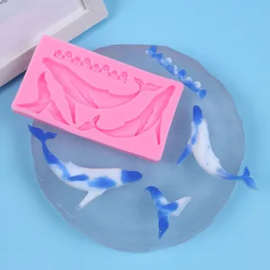 Moule en silicone rose avec formes de baleines et de vagues avec modèles finis en résine.