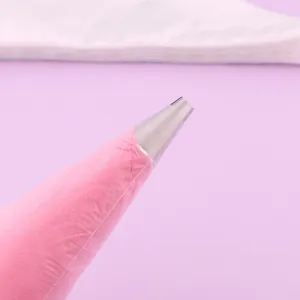 Close-up of a disposable pastry piping bag with metal nozzle filled with pink frosting.