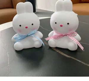 Side view of two cute white rabbit LED night lights with colorful checkered bows
