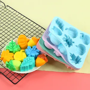 Stack of colorful silicone molds with finished autumn-themed pumpkin and leaf shapes