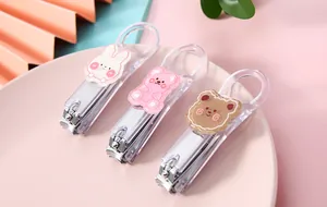 Detailed shot of three cute cartoon nail clippers with animal patches on a pink plate.