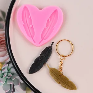 Detalle del molde de silicona de plumas en forma de corazón rosa y dijes de resina DIY