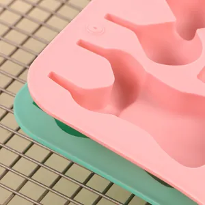 Close-up of pink and green silicone bikini-shaped fondant baking molds on a cooling rack