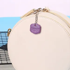 Detalle de un colgante de silicona DIY morado con texto grabado en un bolso crema