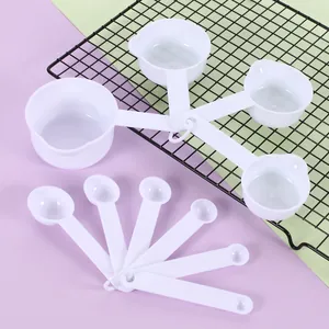 Detailed view of 10-piece white plastic measuring spoon and cup set for baking.