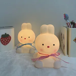 Two adorable rabbit LED night lights with colorful ribbons set on a cozy white rug