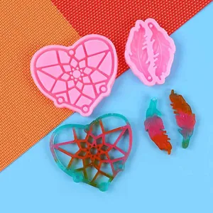 Primer plano de moldes de silicona de corazón y plumas con muestras de resina de colores.