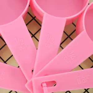 Detailed macro view of pink plastic measuring spoons featuring molded cup scale markings