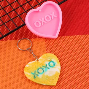 Dettaglio dello stampo in silicone rosa a cuore e del portachiavi in resina con design XOXO