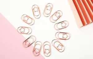 Roségoldene sternförmige Metall-Büroklammern kreisförmig auf rosa Hintergrund angeordnet