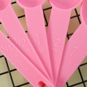 Detail view of pink plastic measuring spoons showing embossed capacity measurements.