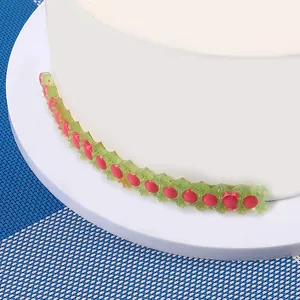 Detail van vintage groen en roze bloemen fondant randversiering op een witte taart