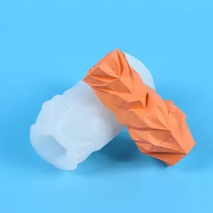 Detailansicht einer geometrischen Silikonform neben einer orangefarbenen Kerze mit Struktur.