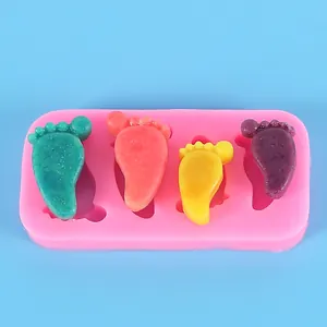 Dettaglio dello stampo in silicone rosa con orme di neonato e modelli in resina colorati