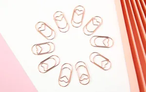 Roségoldene herzförmige Büroklammern, kreisförmig auf einem Hintergrund angeordnet