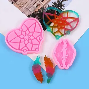 Detalle de moldes de silicona de corazón y pluma con artesanías de resina terminadas