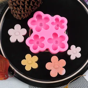 Detail of pink flower-shaped silicone mold with finished fondant flowers on a black plate