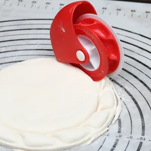 Detailansicht eines roten Teigschneiders beim Crimpen von Teig auf einer Silikonmatte.