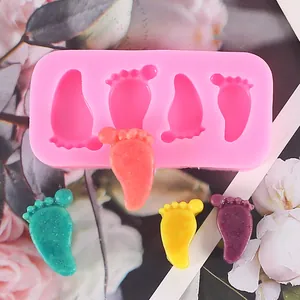 Dettaglio di uno stampo in silicone rosa con forme di piedi di bambino per torte