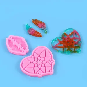 Detalle de moldes de silicona rosa para plumas y atrapasueños con piezas de resina terminadas