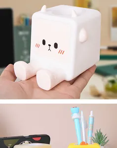 Dettaglio di un simpatico portapenne a cartone animato tenuto in mano e sulla scrivania.