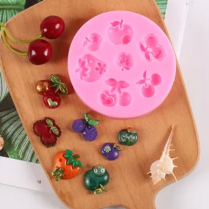 Vogelperspektive einer rosa Silikonform in Fruchtform mit fertigen Harzanhängern auf Holz.