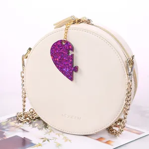Dettaglio di un ciondolo a forma di cuore glitterato viola su una borsa bianca