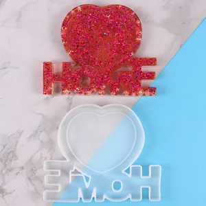 Stampo in silicone cuore e lettere HOME con un campione in resina rossa glitterata.