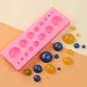 Detailaufnahme einer rosa Silikonperlenform mit blauen und goldenen Perlenproben