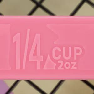 Macro view of functional 1/4 cup markings on a pink plastic measuring spoon detail