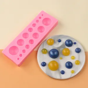Rosa Perlen-Silikonform in verschiedenen Größen mit Fondant-Dekoration auf Marmorplatte.