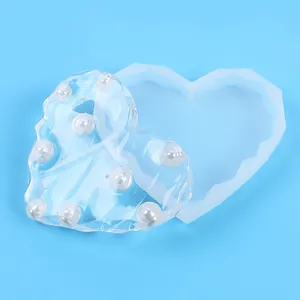Dettaglio stampo in silicone a cuore e sottobicchiere in resina epossidica con perle bianche.
