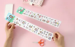 Close-up of cute Japanese style cartoon sticker strips held over a pink background