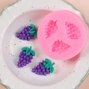 Detailed view of pink grape shaped silicone mold and finished purple grape fondants