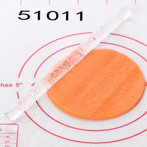 Detail view of transparent acrylic rolling pin with gift pattern on orange fondant