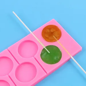 Primer plano del molde de silicona rosa para piruletas con piruletas naranjas y verdes
