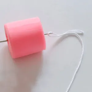 Detailed view of a pink silicone candle mold with a stainless steel wick threading needle
