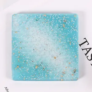 Détail de dessous de verre carré en résine bleue avec paillettes et feuilles d'or