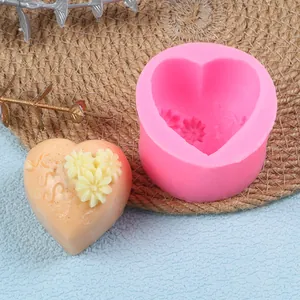 Close-up of a pink heart-shaped silicone mold next to a finished 'Kiss' floral cake