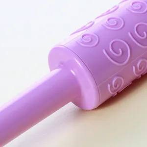Close-up of a purple plastic rolling pin with an embossed spiral pattern for fondant